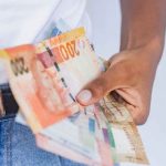 a person holding a bunch of money in their pocket