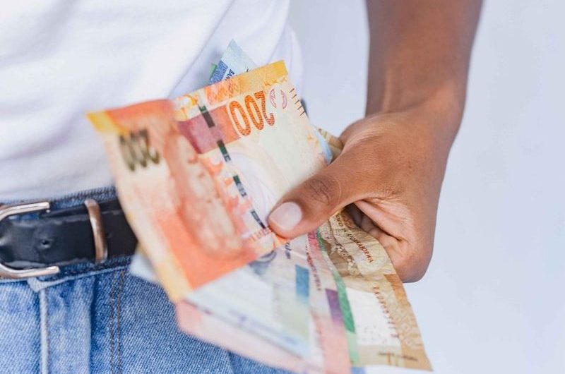 a person holding a bunch of money in their pocket